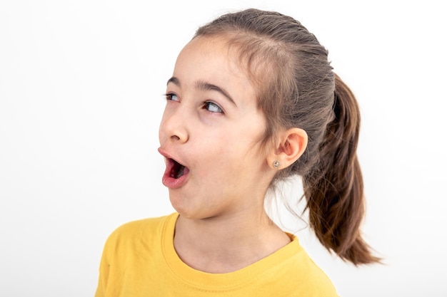 Free photo little girl looks to the side in surprise on a white background isolated