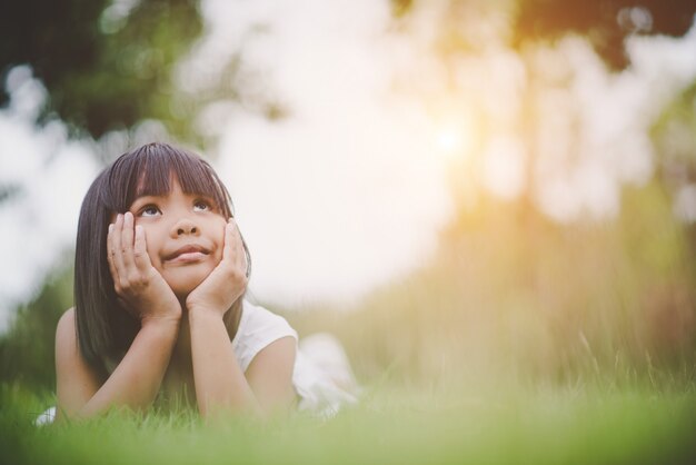 Маленькая девочка, удобно лежащая на траве и улыбаясь