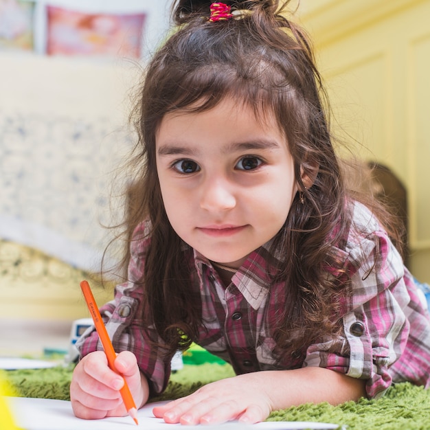 Little girl lying on the floor and drawing