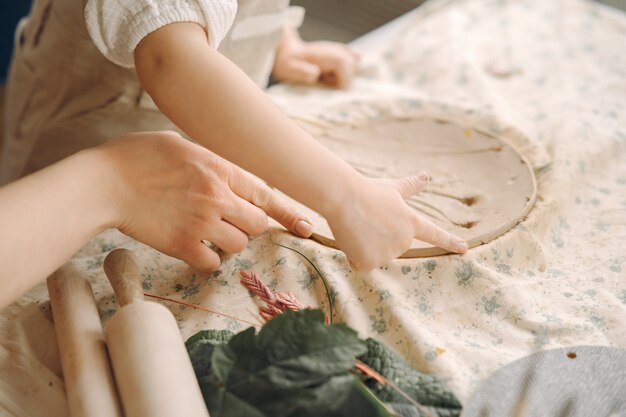 Little girl makes a clay plate and decorates it