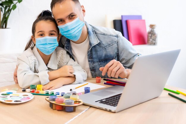 маленькая девочка в медицинской маске учится дома. эпидемия, пандемия.