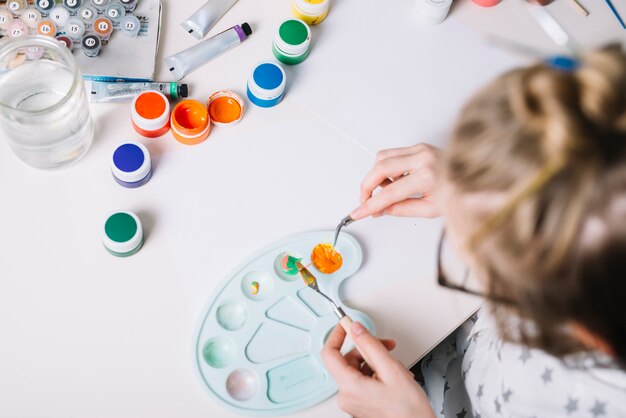 Little girl mixing gouache on palette 