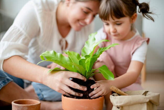 家で小さな女の子とお母さんの鉢植え植物