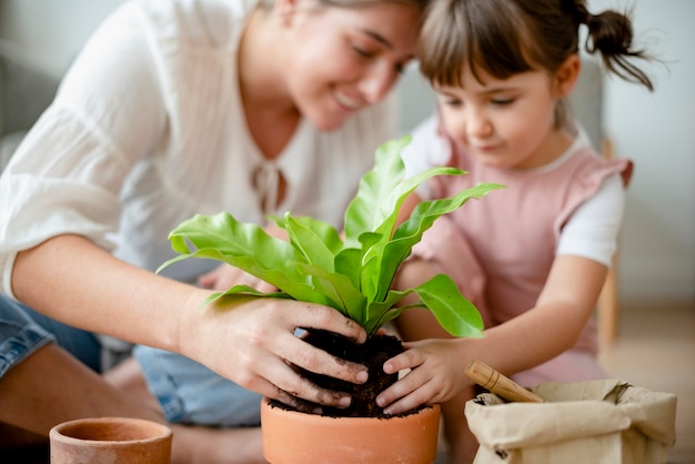 家で小さな女の子とお母さんの鉢植え植物