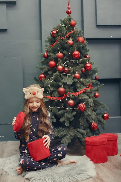 Little girl near christmas tree in a blue pajamas