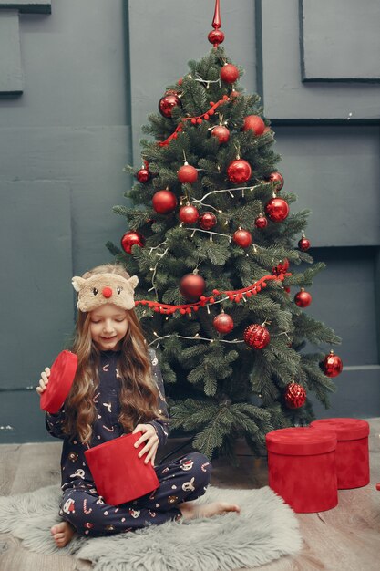 Little girl near christmas tree in a blue pajamas