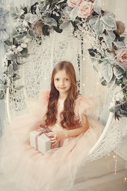 Little girl near christmas tree in a pink dress