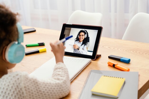 Little girl during online school with tablet and headphones