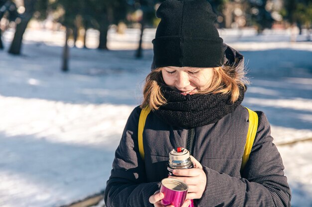 Маленькая девочка на улице с термосом в холодный зимний день
