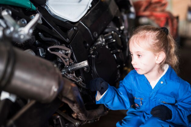 Little girl in overall inspecting bike 