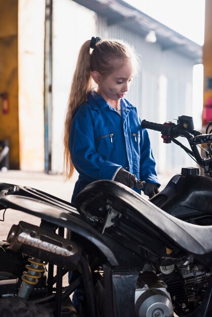 Little girl in overall inspecting quad bike 