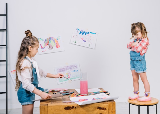 Little girl painting girl on chair 