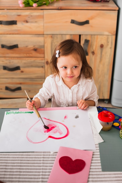 Бесплатное фото Маленькая девочка рисует сердце на бумаге