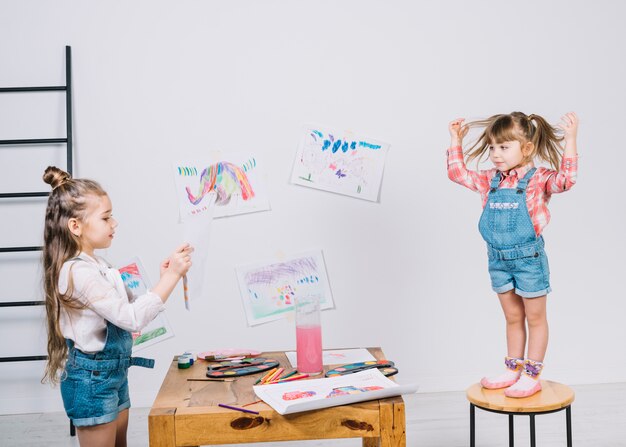 Little girl painting posing girl on chair