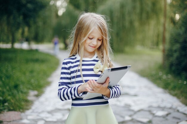 Little girl in a park playing with a tablet