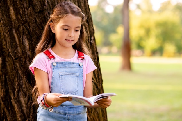 little girl in the park reading a book