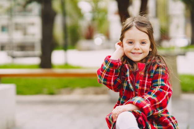 Little girl in a park sitting on a bench