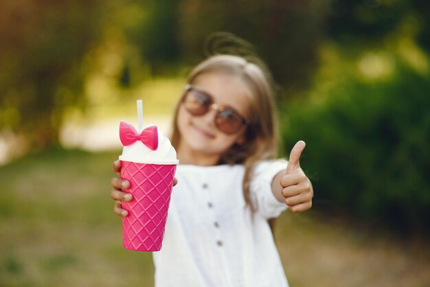 Little girl in a park standing with pink cup