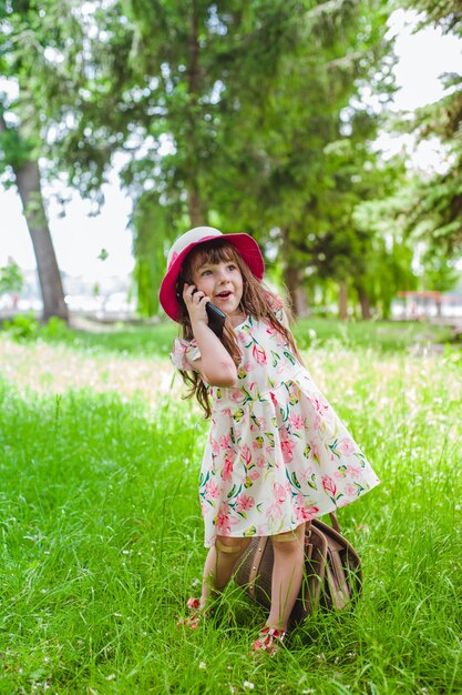 電話でバッグと話す公園内の小さな女の子