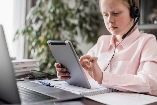 Маленькая девочка участвует в онлайн-классе на дому при использовании планшета