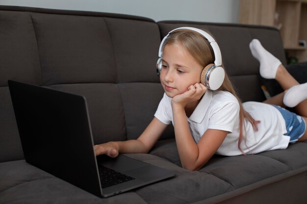 Маленькая девочка участвует в онлайн-классах с наушниками