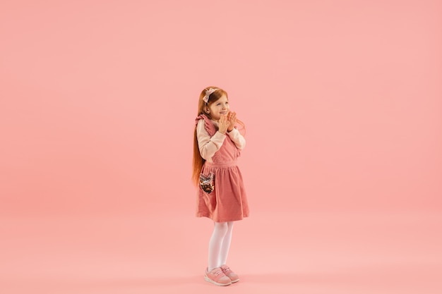 Little girl in pink dress on pink wall