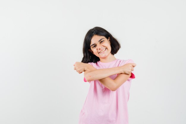 Little girl in pink t-shirt stretching arms and looking optimistic , front view.