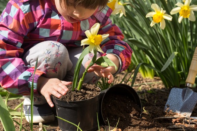 정원에서 꽃을 심는 어린 소녀
