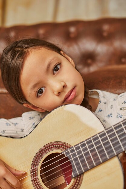 Little girl playing guitar at home