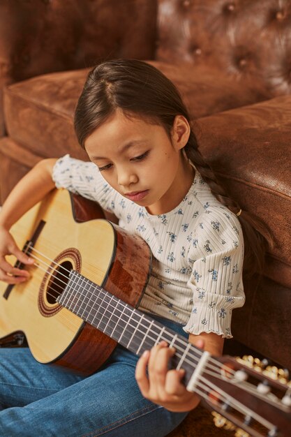 家でギターを弾く少女