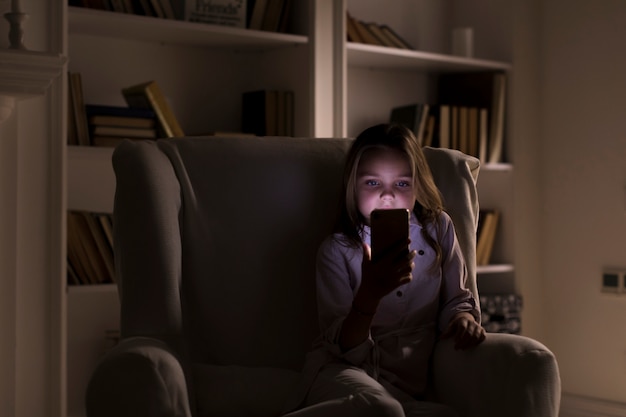 Little girl playing on her phone indoors