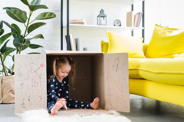 Free photo little girl playing inside cardboard box