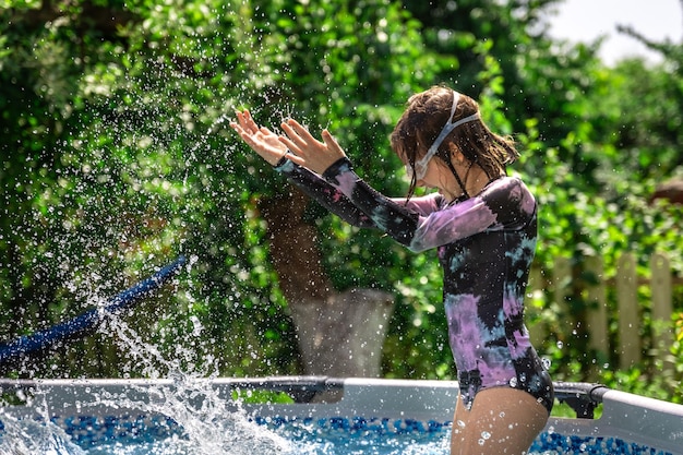 Foto gratuita piccola ragazza che gioca in una piscina in un giardino estivo