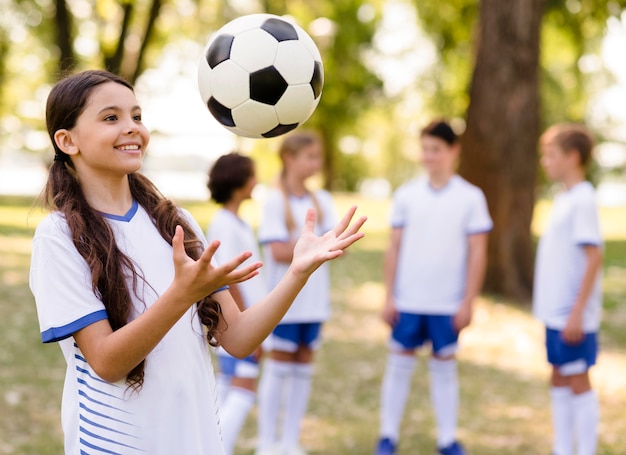 Foto gratuita bambina che gioca con un pallone da calcio all'esterno