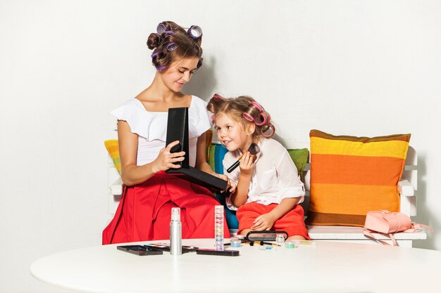 Little girl playing with her mom's makeup on white