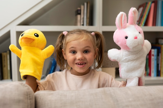 Little girl playing with her puppets at home