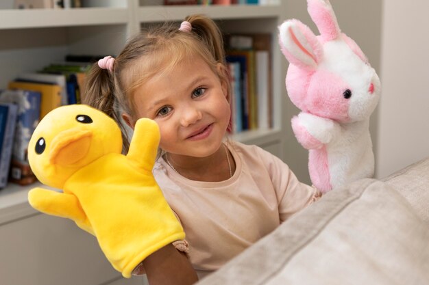 Маленькая девочка играет со своими куклами дома