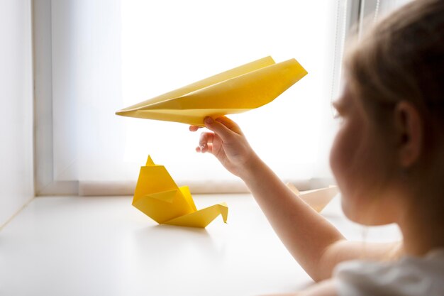 Маленькая девочка играет с бумагой оригами дома