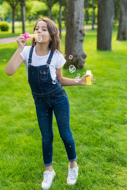 Free photo little girl playing with soap bubbles outdoors