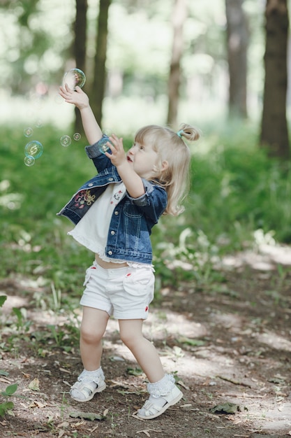 Маленькая девочка, играя с мыльными пузырями