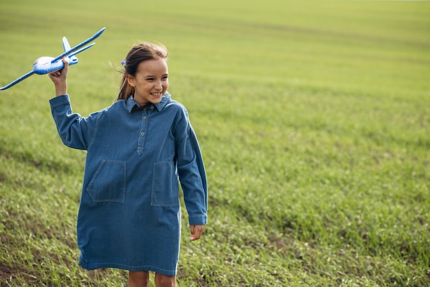 Маленькая девочка играет с игрушечным самолетом в поле