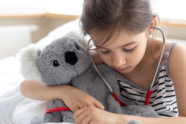 A little girl plays doctor with her favorite soft toy