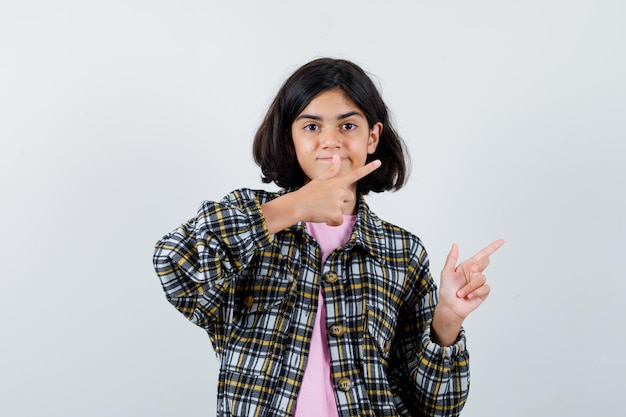 Little girl pointing aside in shirt,jacket , front view.