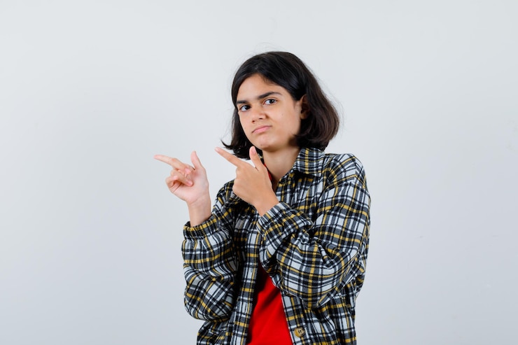 मुफ़्त फोटो little girl pointing aside in shirt,jacket and looking displeased. front view.