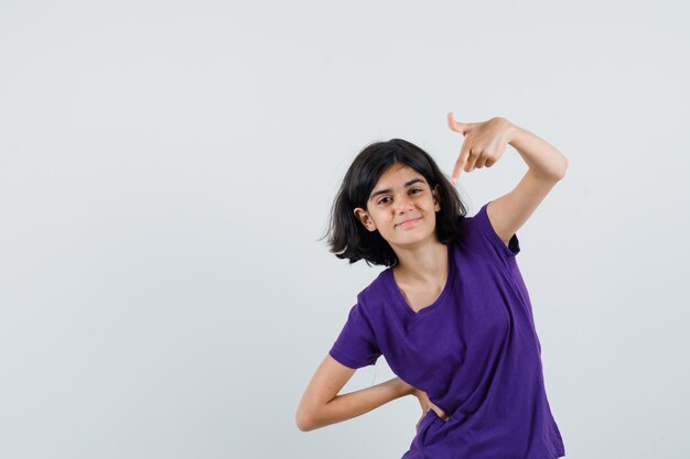 Little girl pointing down in t-shirt and looking confident