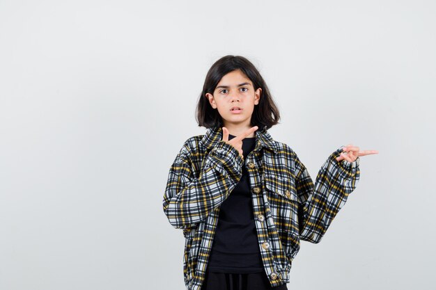 Tシャツ、ジャケットで右側を指して自信を持って見える少女。正面図。