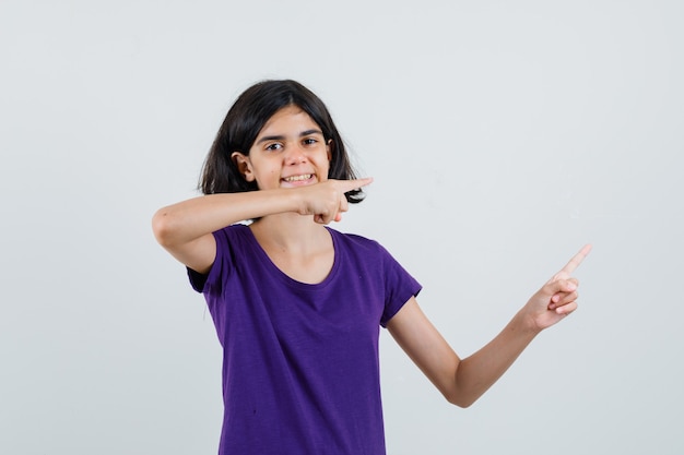 Bambina che indica il lato in maglietta e che sembra allegra