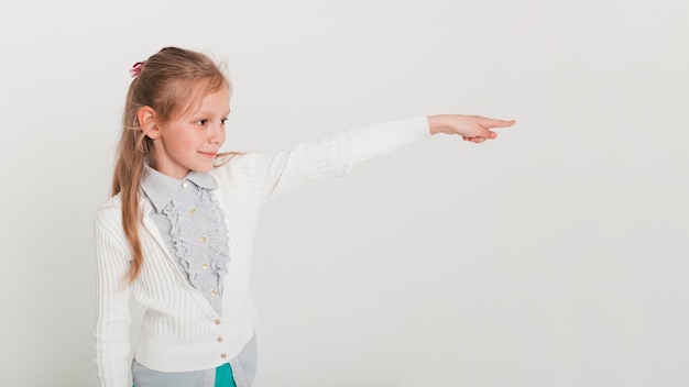 Free photo little girl pointing towards copyspace