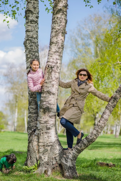 어린 소녀는 나무에 그녀의 어머니 옆에 포즈