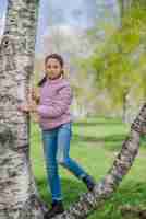 Free photo little girl posing on a tree trunk